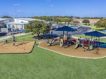 aerial shot of a park with two blue covers with a few small children playing in the distance