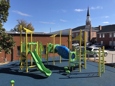 picture of yellow park with lime green slides with a church in the background