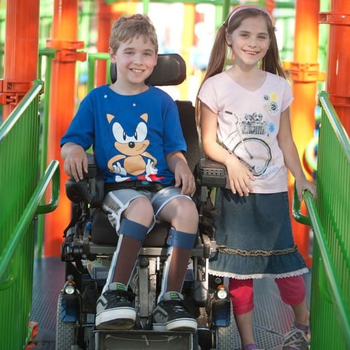 two children smiling on playground bridge