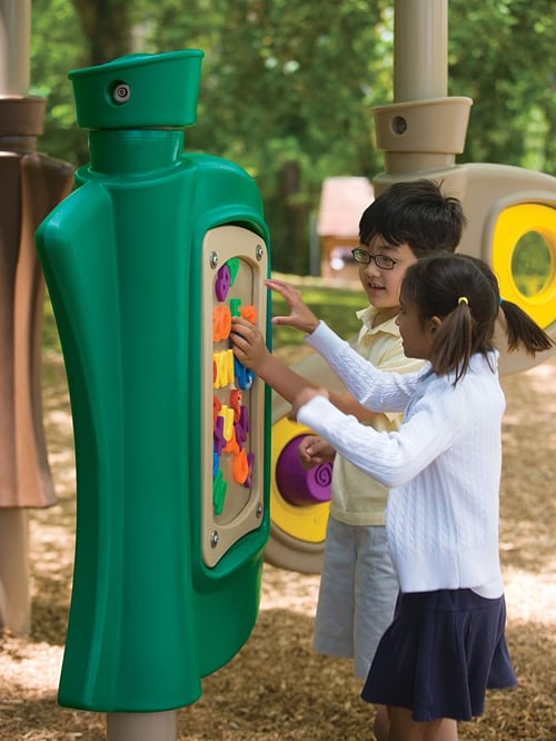 two children playing on a green playground equipement