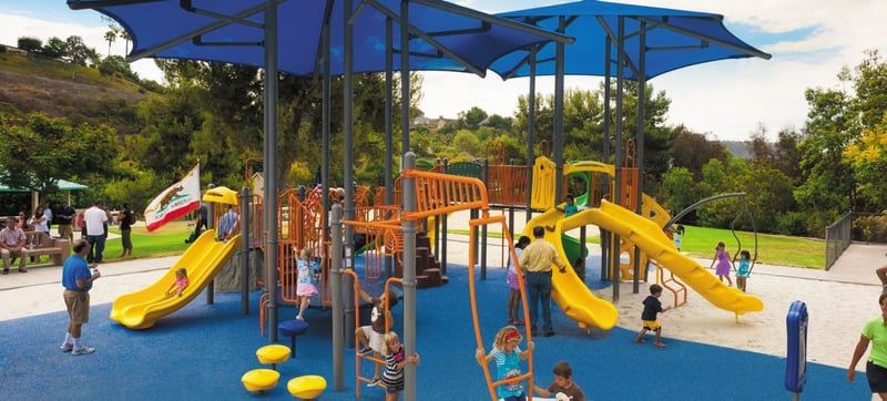 blue and yellow colored park with large blue overheads and children playing on the park