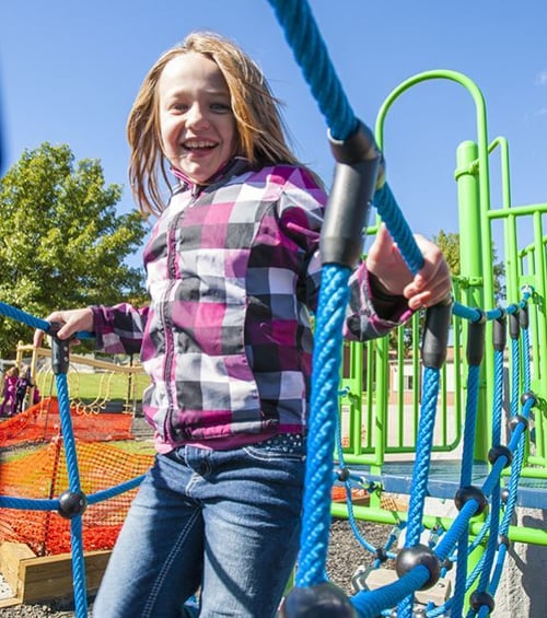 small child in purple outfit smiling playing at park