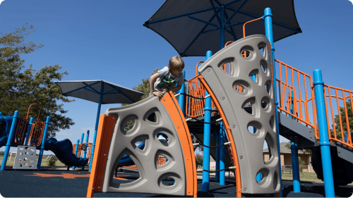 young child climbing on gray climbing structure at playground