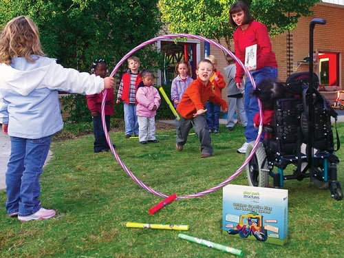 small children playing in a yard throwing things through a hoola hoop