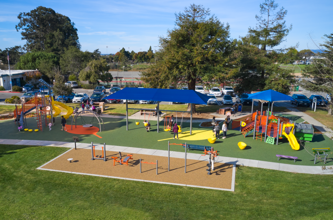 Elm Street Park with yellow, orange, green, and blue playground equipment and adults and kids playing