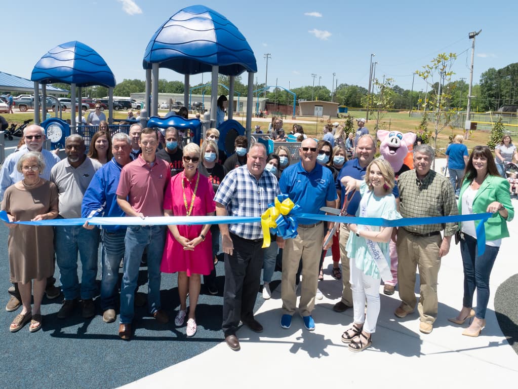 large group of people doing a grand opening and ribbon cutting at playground park