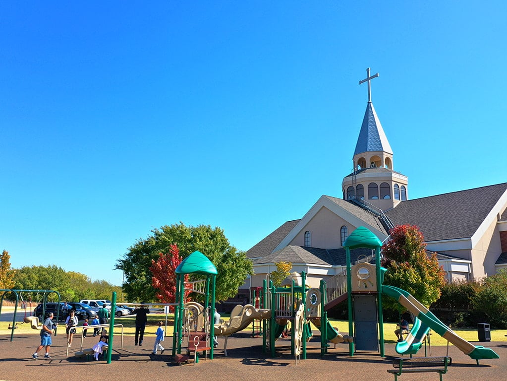 green colored playground with a large white church in the background