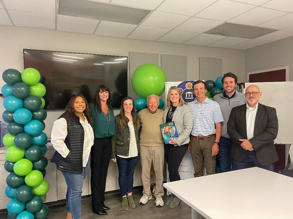 group of colleagues smiling next to green balloons 