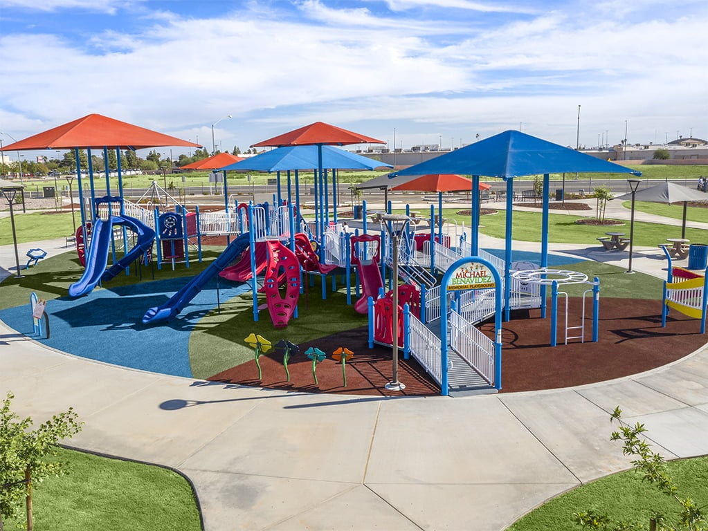 aerial shot of Michael Benavidez Memorial Playground that has blue and light red top slides and covers