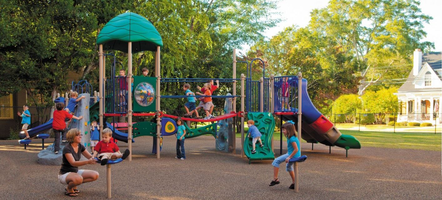 Featured image of small children playing at a colorful park in front of large trees