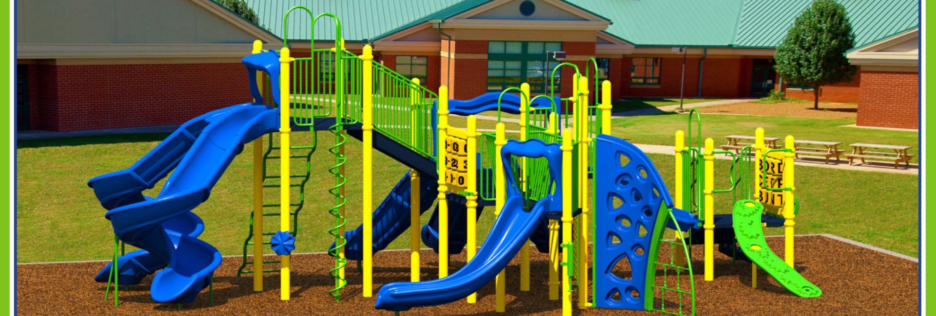 Park with lime green, yellow, and blue slides in front of Elementary School 