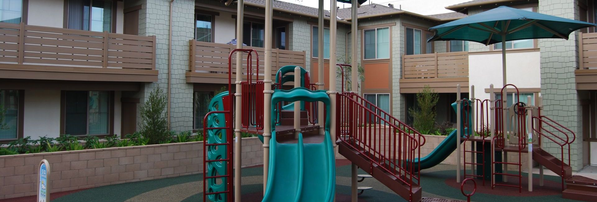 park in middle of apartment complex with green slides and yellow railing