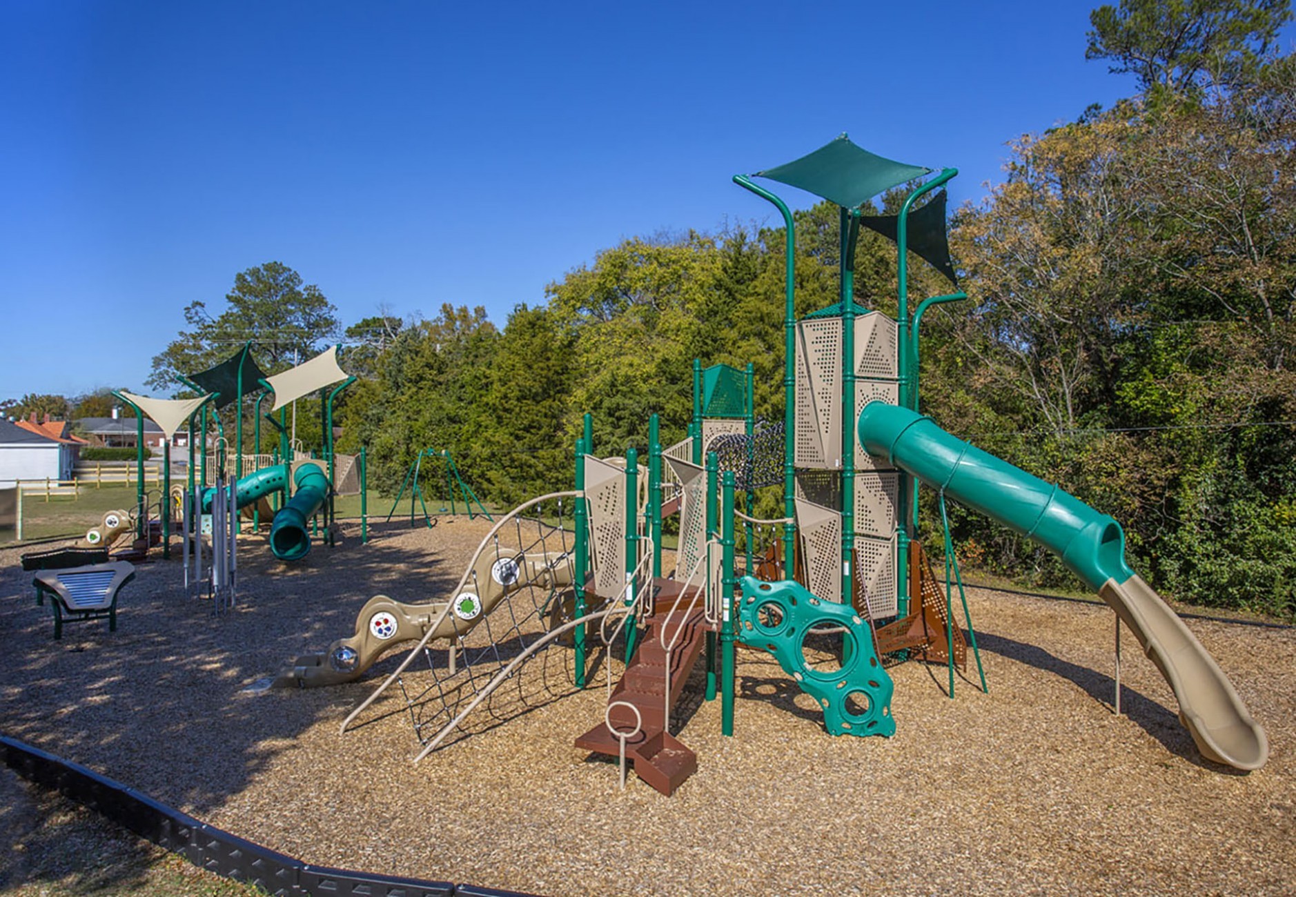 image of brown and green colored themed playground in front of trees