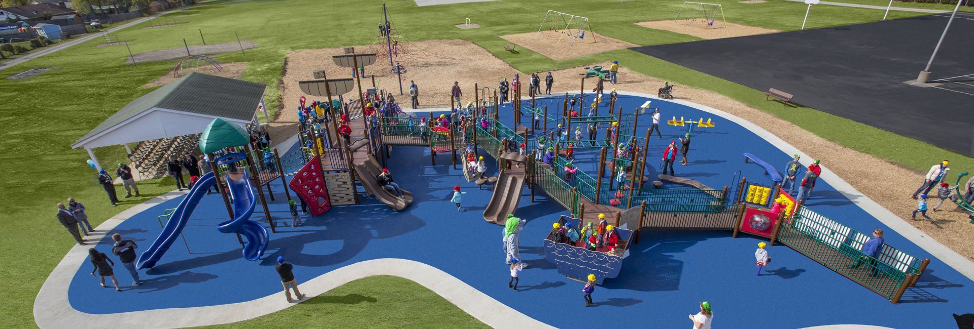 Aerial view of park on blue turf with several children playing on it