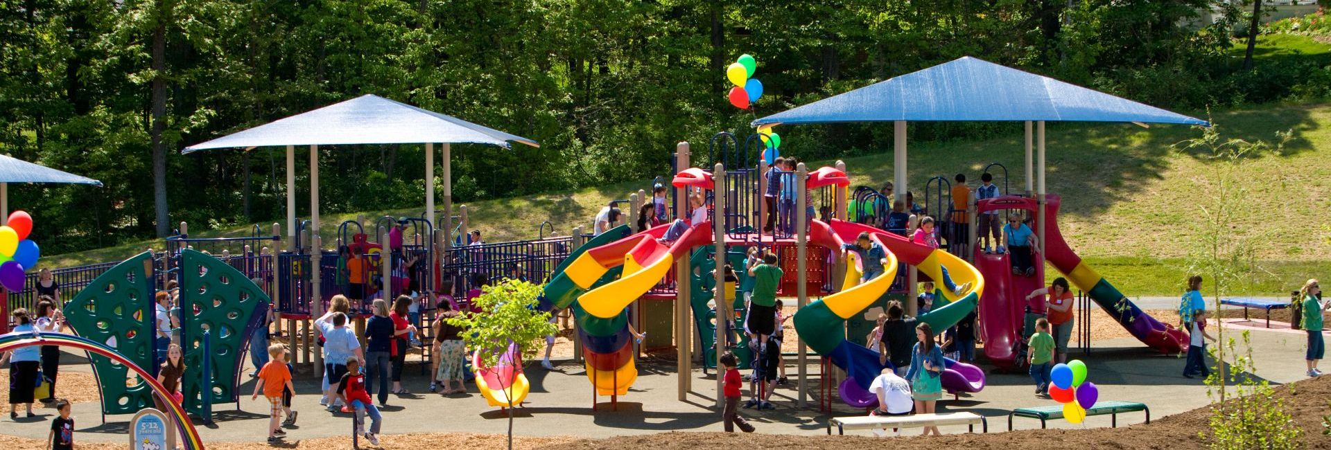 Children playing on green, yellow, and red patterned slides at park