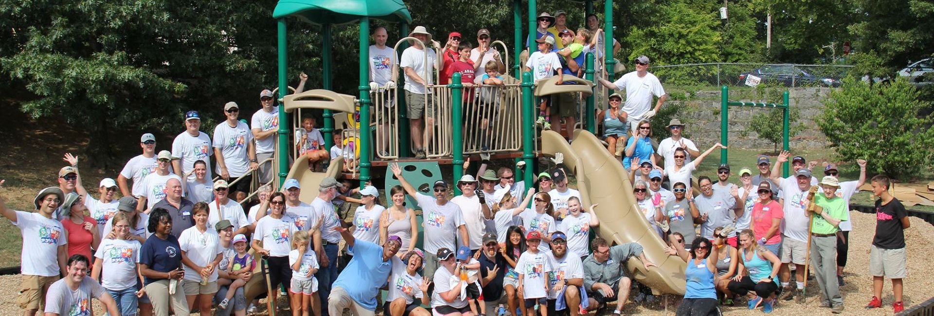 Large group of people smiling at grand opening of playground