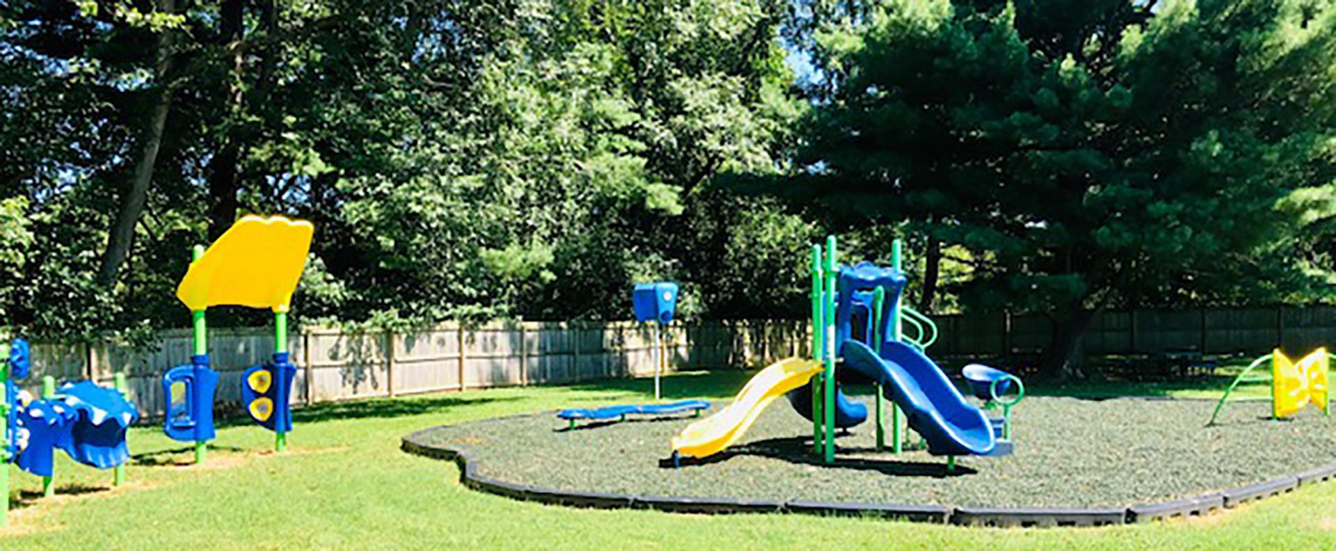 Featured image of playground with a blue slide during the summer and trees in background