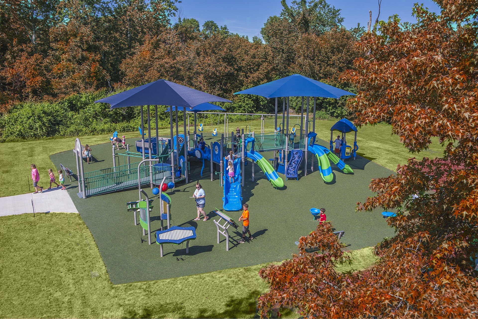 aerial shot of a blue and green colored park with children playing on it during the fall