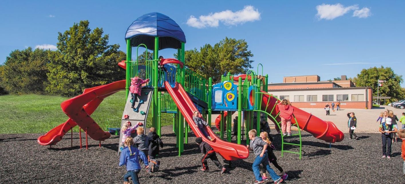 children playing on a blue green playground with red slides during sunny day