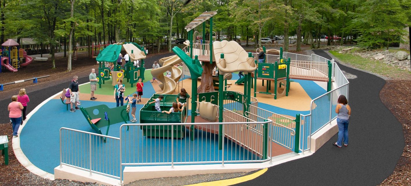 aerial shot of children playing on a large green and tan colored park with blue turf