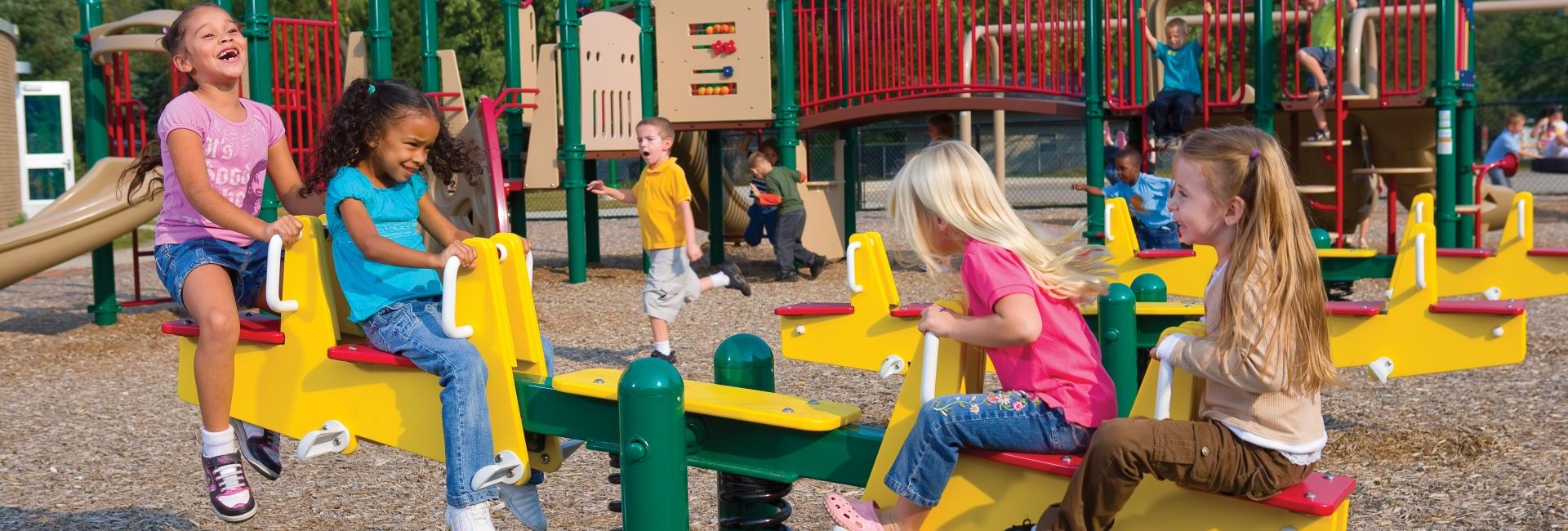 Two children playing on yellow seesaw at park