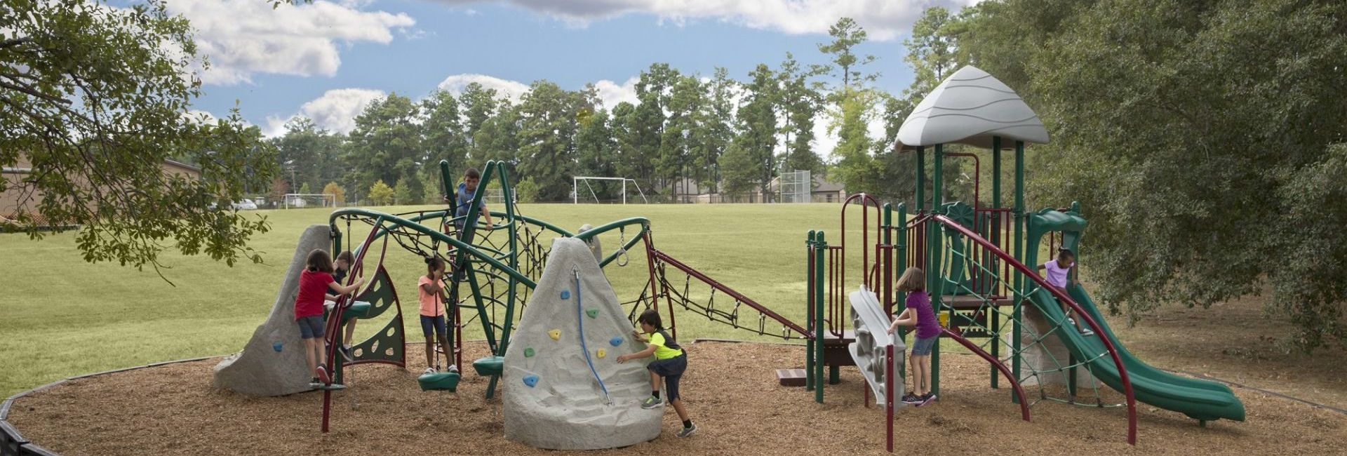 Featured image of children playing at playground with a small gray climbing rock