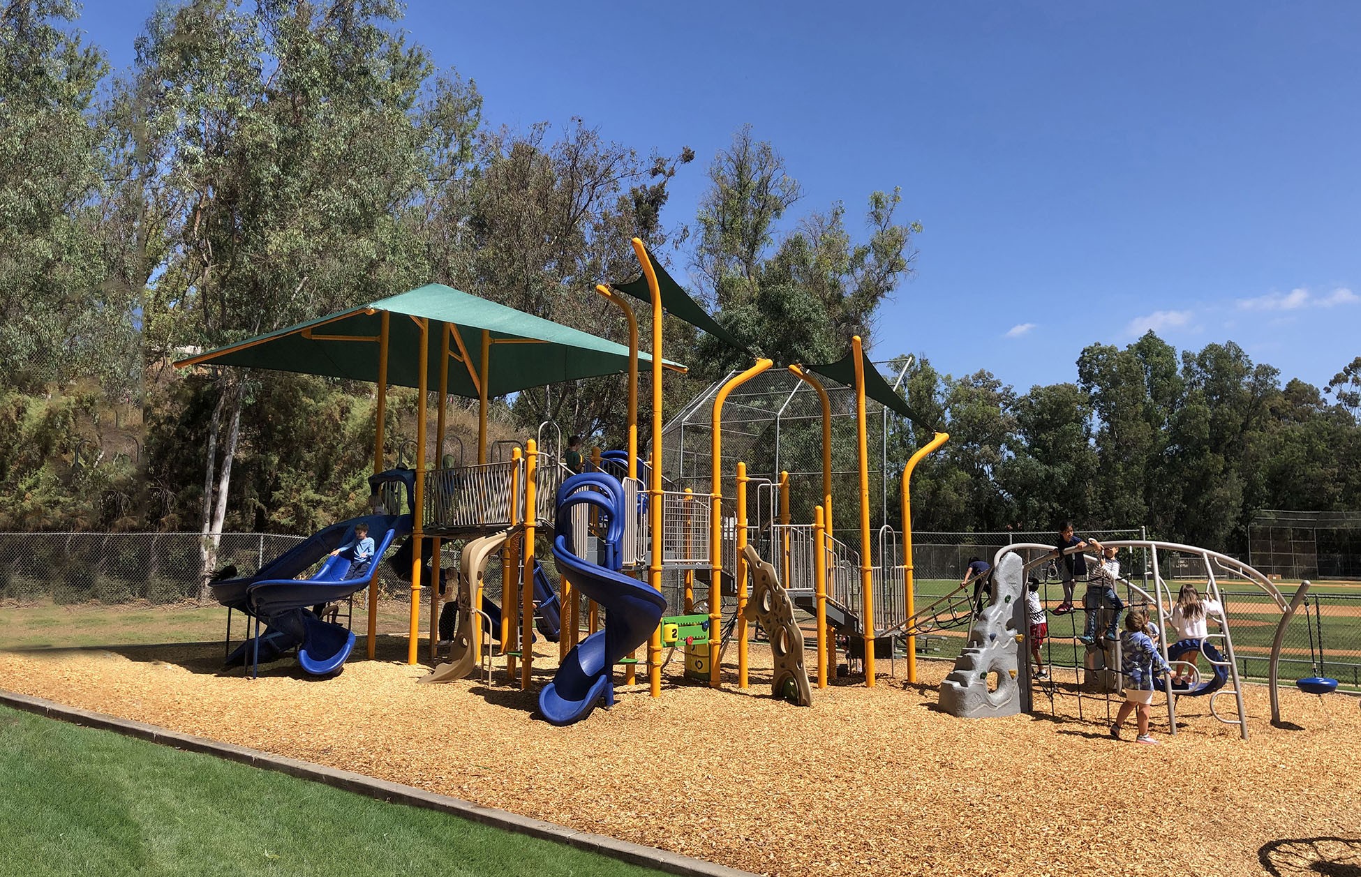 yellow colored playground with children playing on swings in the corner