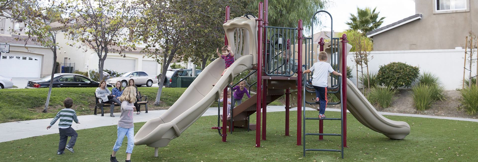 maroon colored park with gray slide and children playing on it