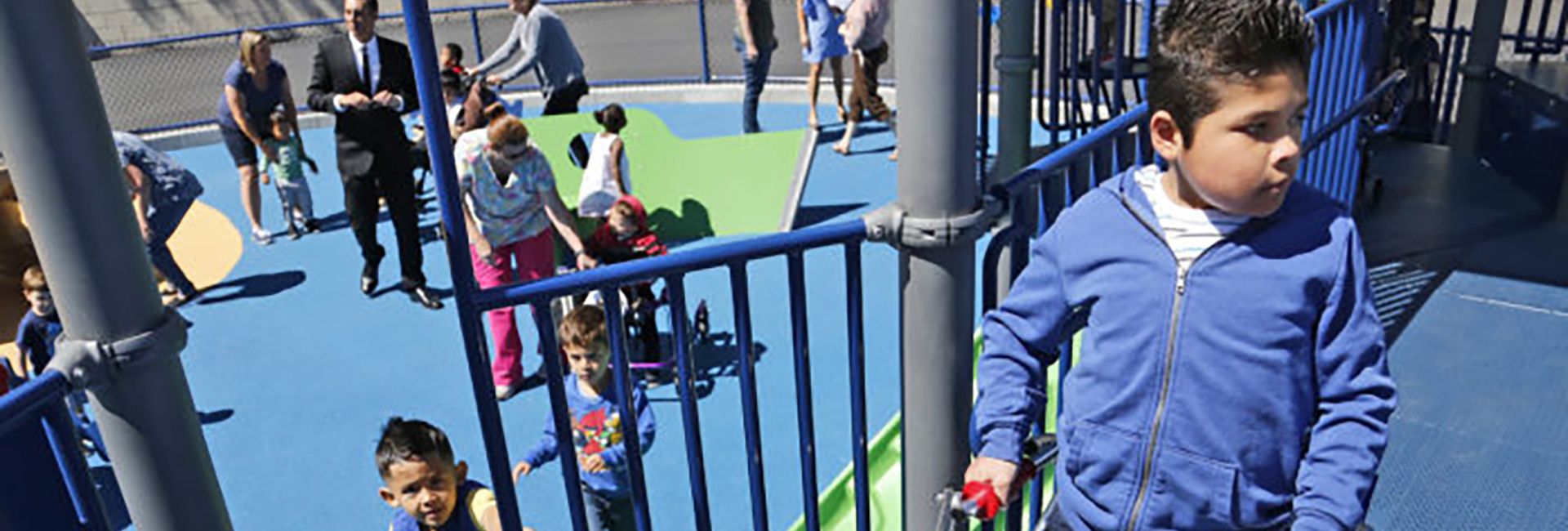 Featured image of Children with their mothers playing at park with blue and green turf