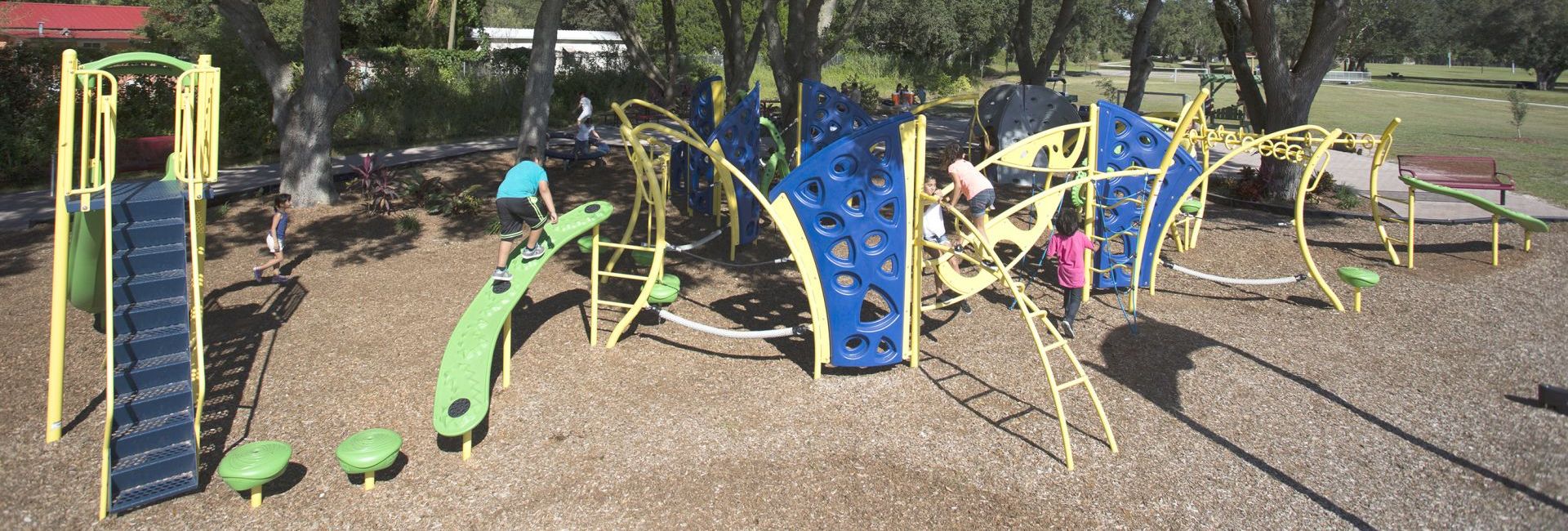 Children playing on yellow, blue, and green climbing object at park