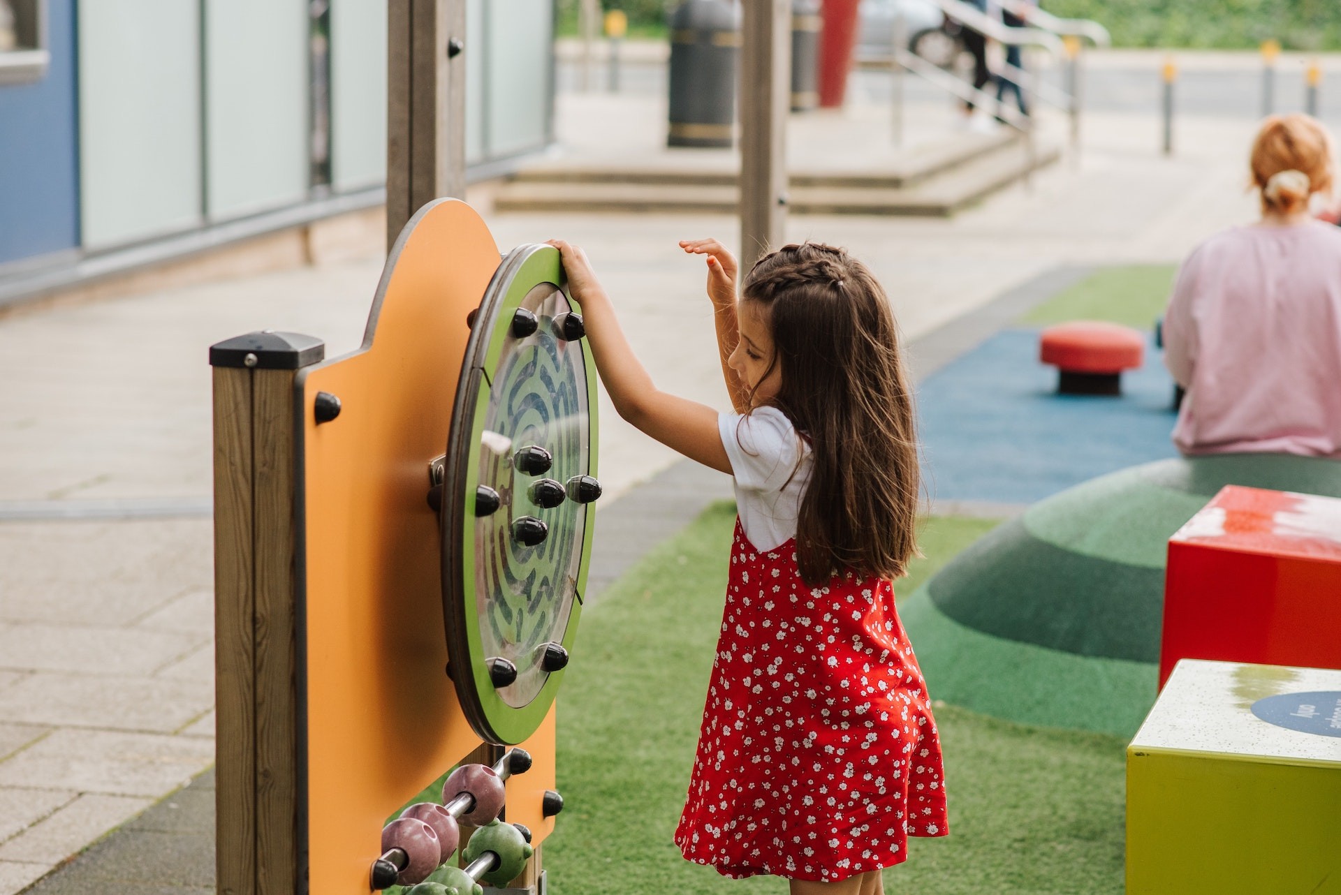 Child in red dress spinning a play wheel on playground