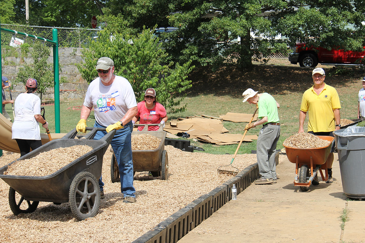 Volunteers in colorful shirts working on playground 