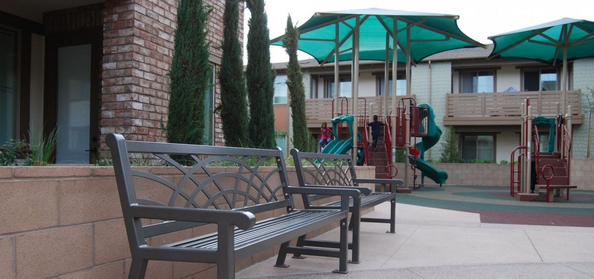 close up of gray benches with nice designs and green playground in background