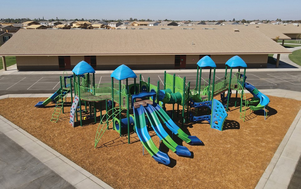 Grasslands Elementary School with blue and green slides on brown turf