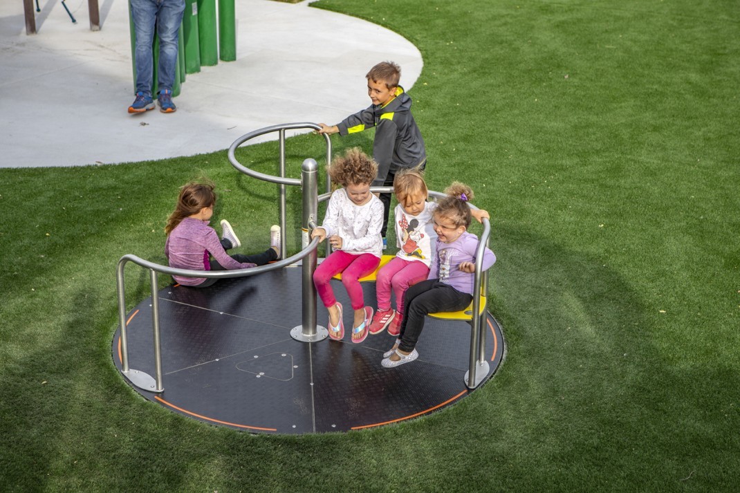 children playing on mary-go-round at park