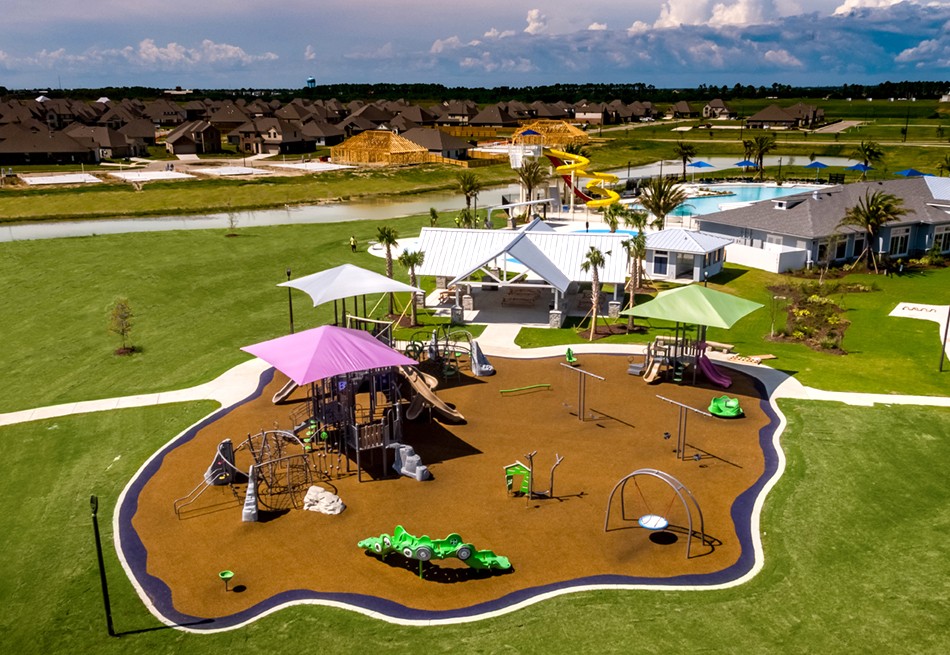 Featured image of Aerial view of a park with brown flooring and pink, white, and green covers on top of the structures