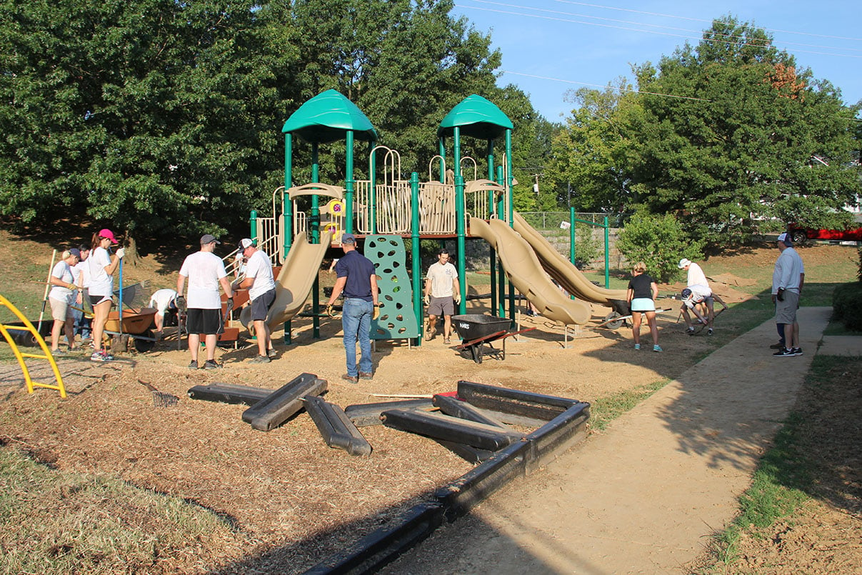 Volunteers pouring dirt around new playground
