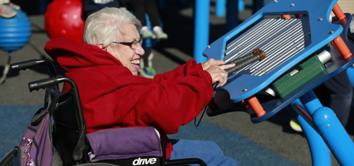 Elderly woman in wheelchair smiling playing instrument at park