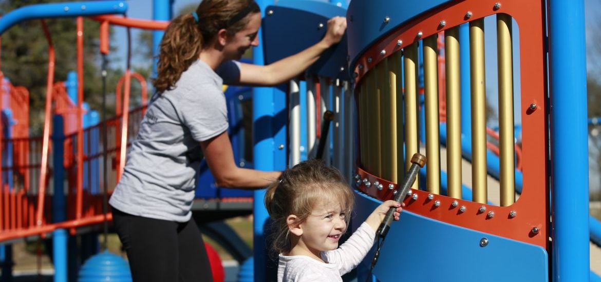 Mother and daughter in white t shirts playing on instrument at park