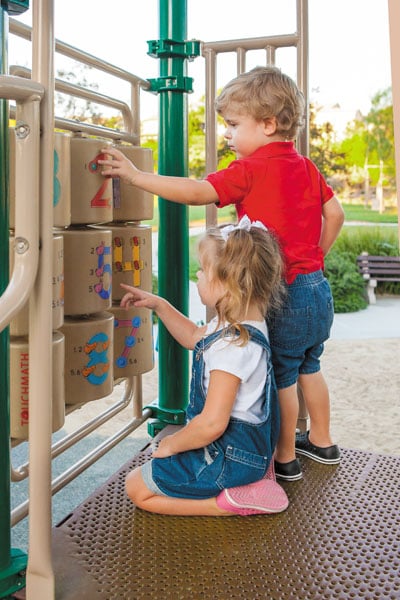 Young boy and girl playing with TouchMath Activity Panel on a playground