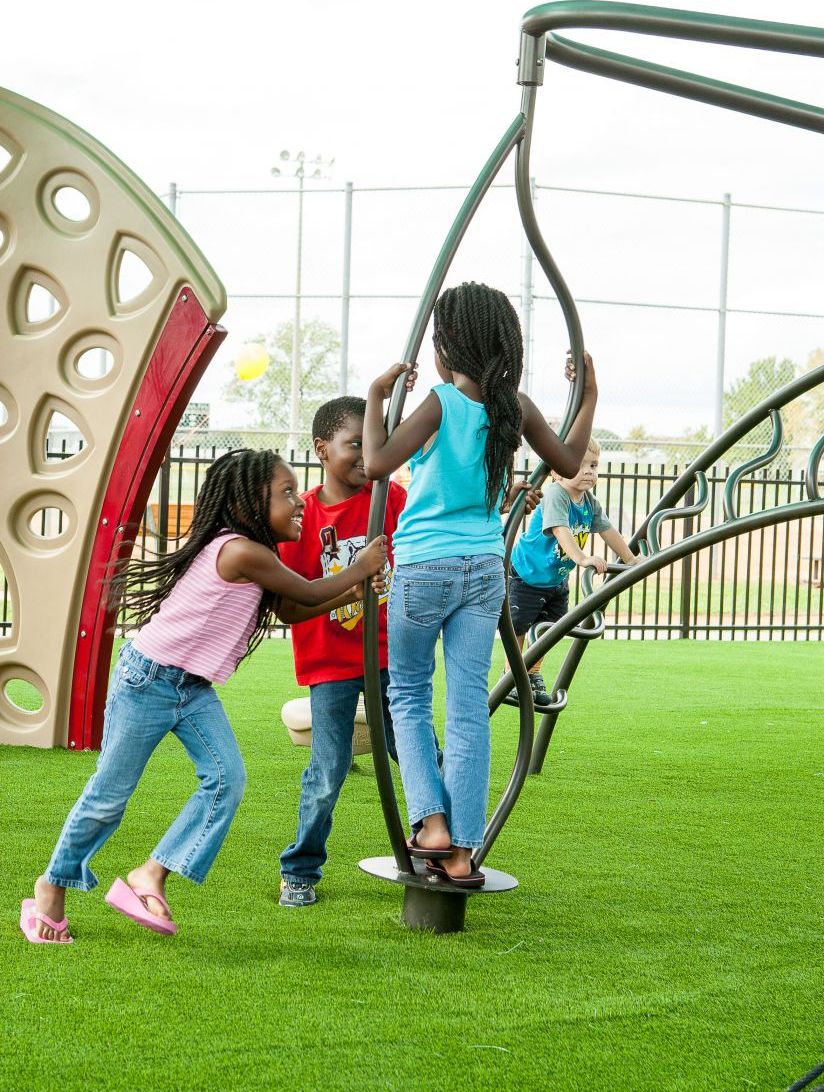 2 young boys and 2 young girls playing on outdoor playground equipment and SurfaceMax Play Turf