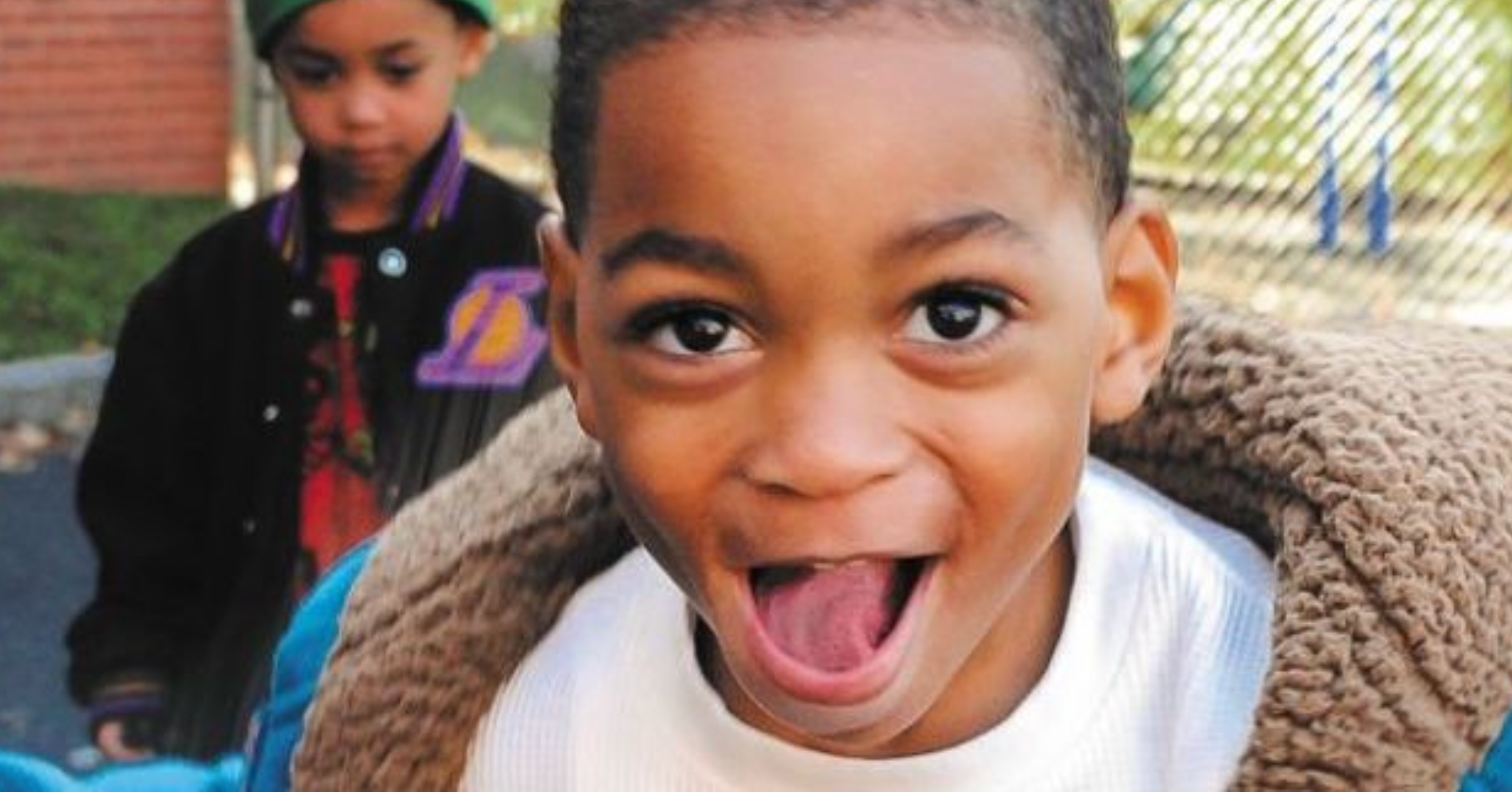 Two boys in jackets, one smiling and looking at the camera