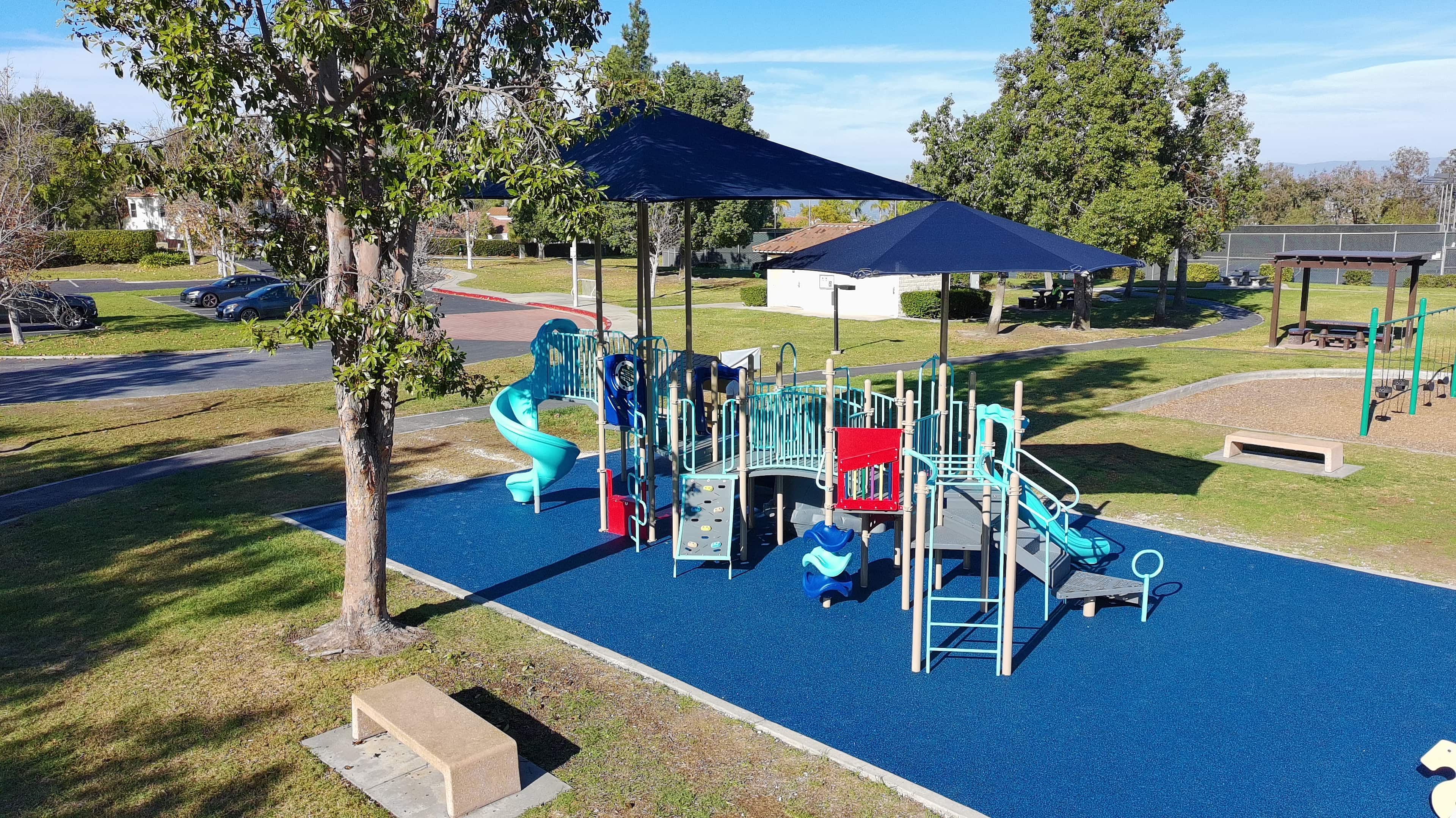 Featured image of Aerial view of a modern playground with slides, climbing structures, and shade canopies in a landscaped community park.